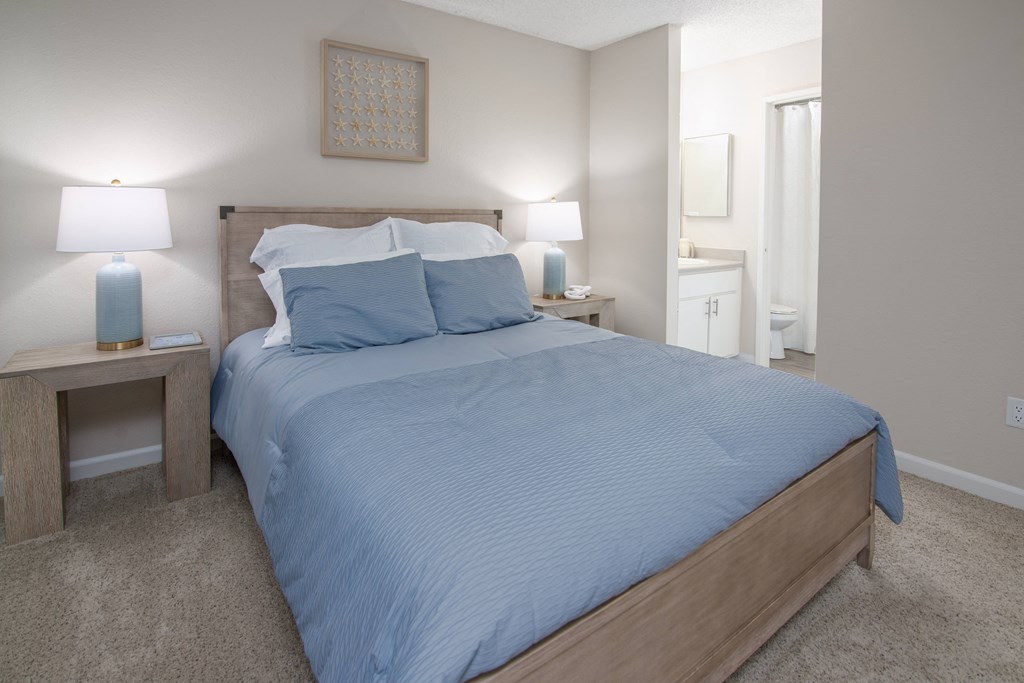 Model Apartment bedroom with a bed and two night stands and a bathroom at Willow Grove Apartments, Sacramento, CA 95825