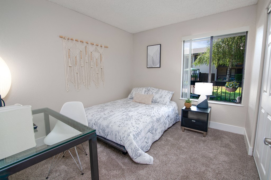Model apartment spare bedroom with a bed and a desk and a window at Rivercrest Apartments, California, 95826