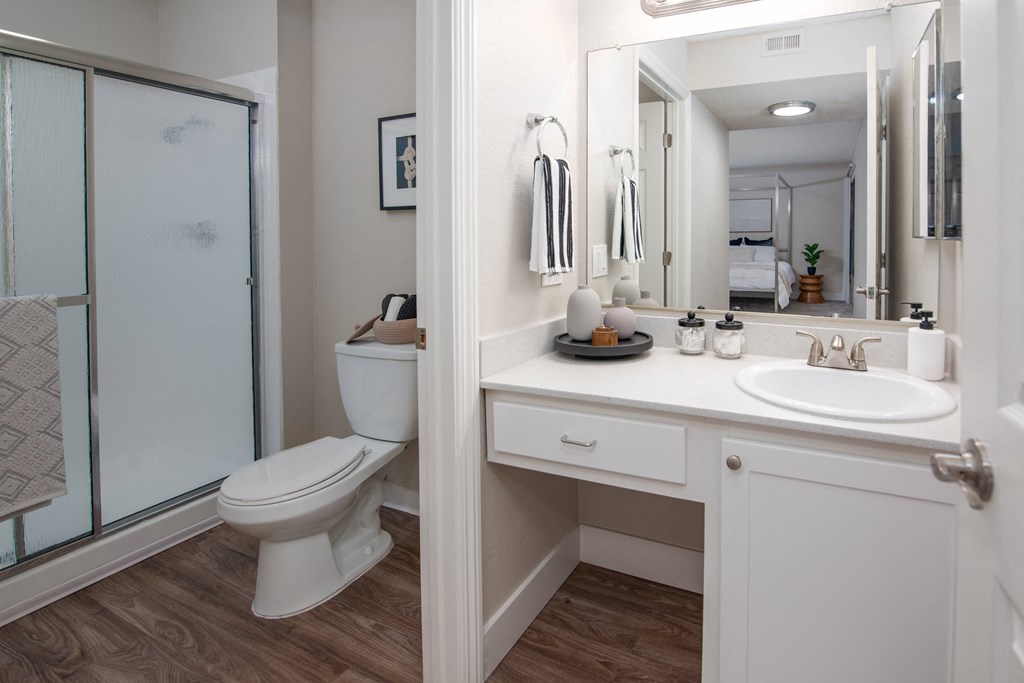 Model apartment bathroom with a shower toilet and sink and a mirror at Rivercrest Apartments, Sacramento California 