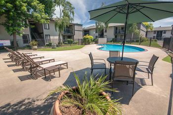 A large pool and patio with chairs and umbrellas at Rivercrest Apartments, Sacramento, CA 95826 
