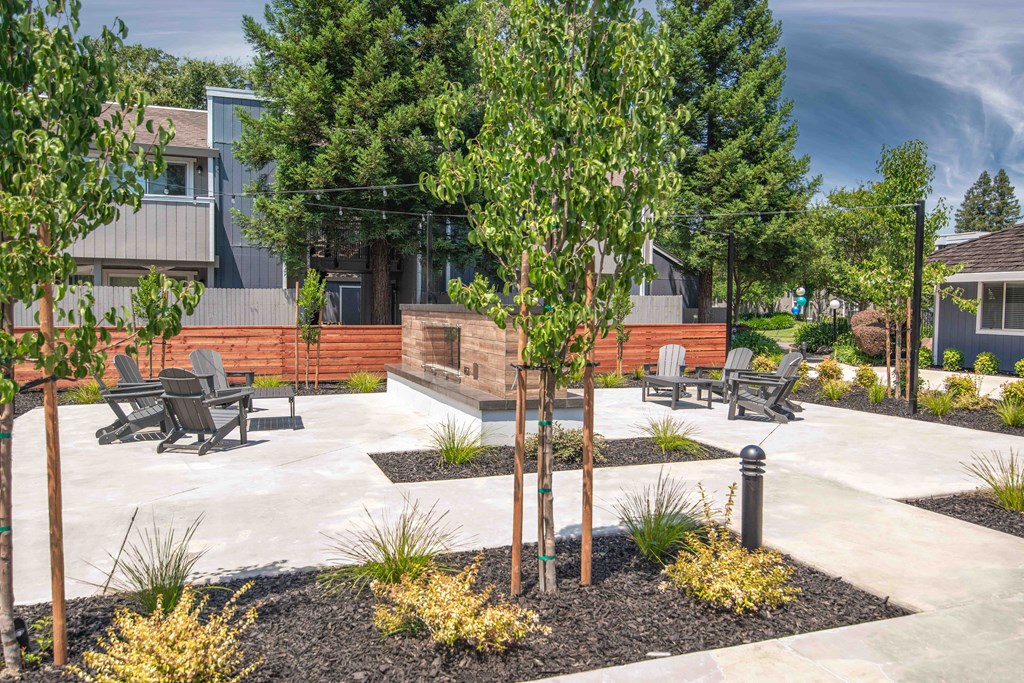 Resident courtyard with benches and trees in front of a fireplace at Willow Grove Apartments, Sacramento California 