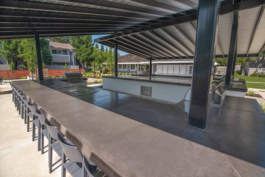 Resident outdoor kitchen with a long table and chairs at Willow Grove Apartments, Sacramento, CA 95825