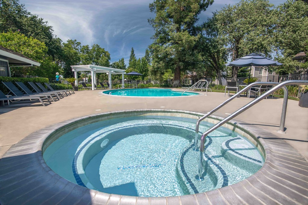 Pool with a hot tub and lounge chairs at Willow Grove Apartments, Sacramento 