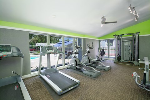 Willow Grove Fitness Center Fitness Center with cardio equipment and windows overlooking a pool at Willow Grove Apartments, California