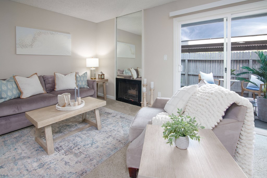 Model apartment living room with a couch and a coffee table and patio door at Willow Grove Apartments, Sacramento, CA