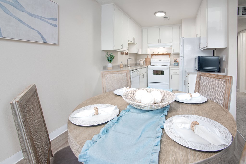 Model apartment dining room table and a kitchen in the background at Willow Grove Apartments, Sacramento, CA 