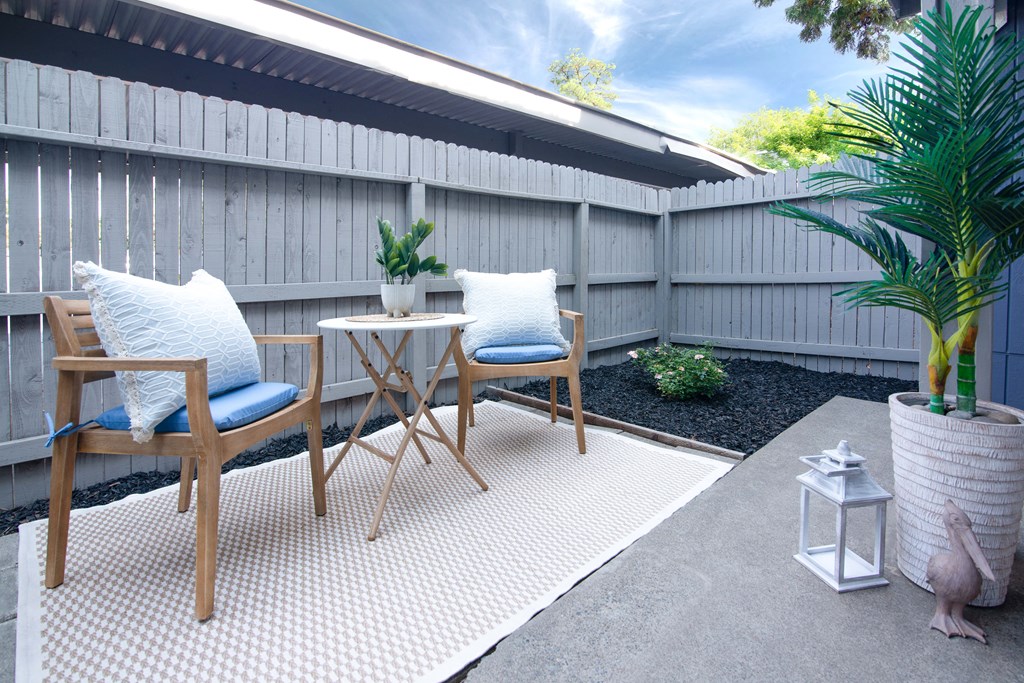 Model Apartment patio with two chairs and a table on a rug at Willow Grove Apartments, Sacramento