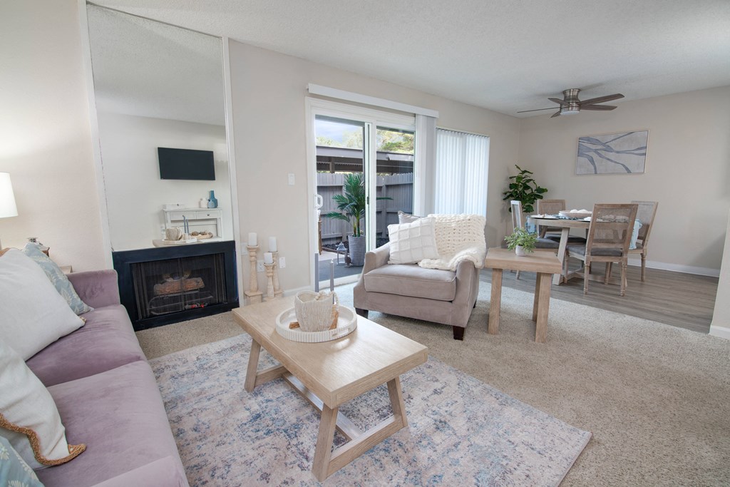 model apartment living room with a couch and a chair and a fireplace and dining room at Willow Grove Apartments, Sacramento, 95825