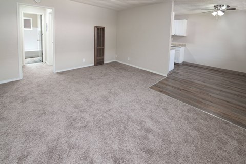 an empty living room with carpet and a kitchen