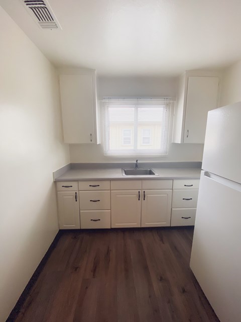 A kitchen with white cabinets and a white fridge.