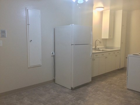 an empty kitchen with a refrigerator and a sink