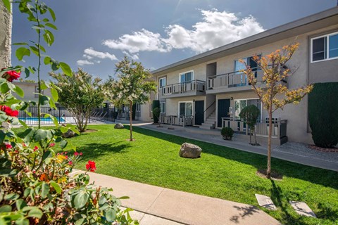 A sunny day at a residential complex with a pool and greenery.