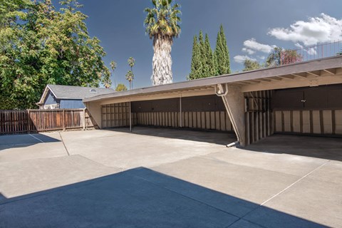 A concrete patio with a building and trees in the background.
