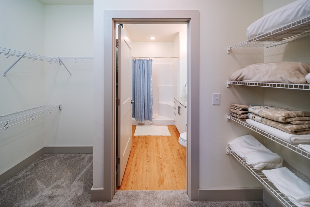 a walk in closet with shelves and a door to a bathroom