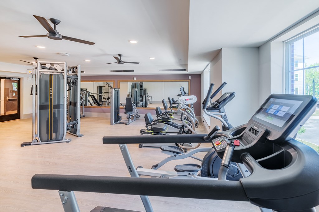 a gym with treadmills and other exercise equipments and a window