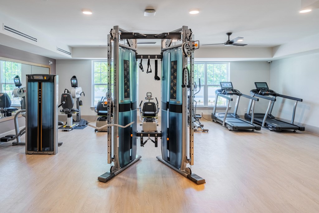 a gym with cardio machines and weights in a room with windows
