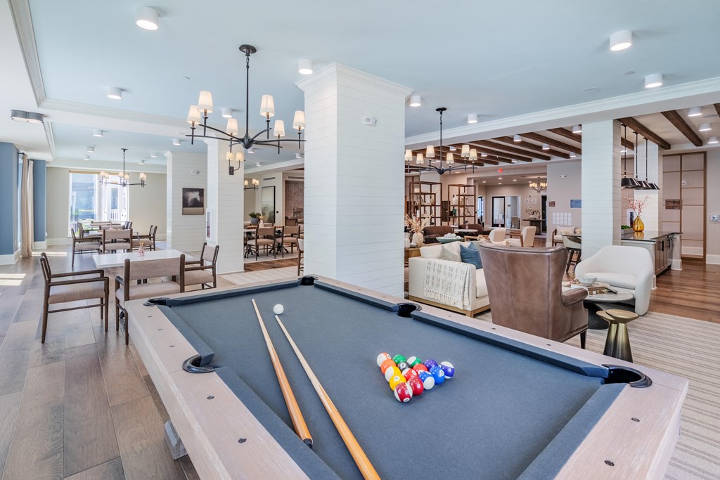 a community room with a pool table and chairs and a dining area