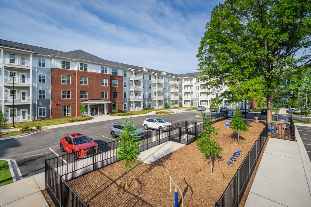 an exterior view of an apartment complex with cars parked in a parking lot