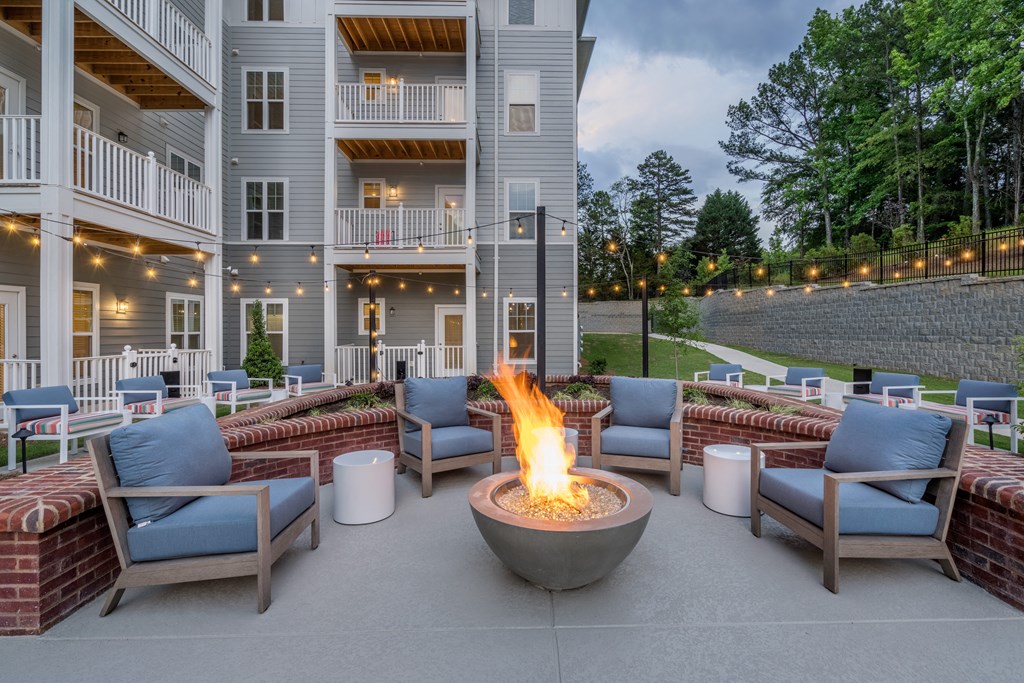 a fire pit in the middle of a patio with chairs and tables