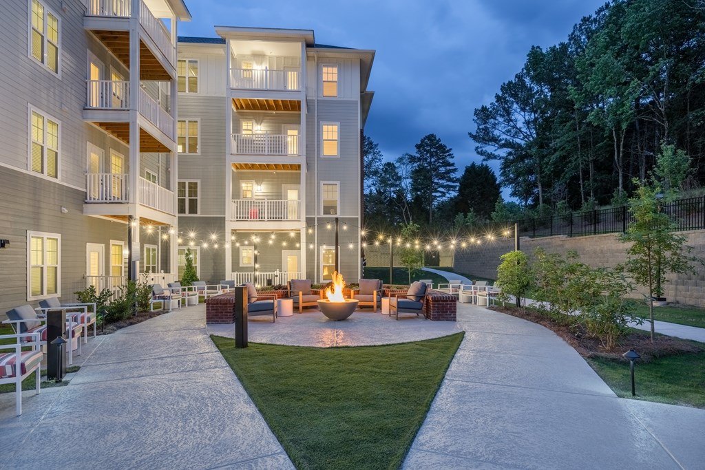 an outdoor living area with a fire pit in front of an apartment building