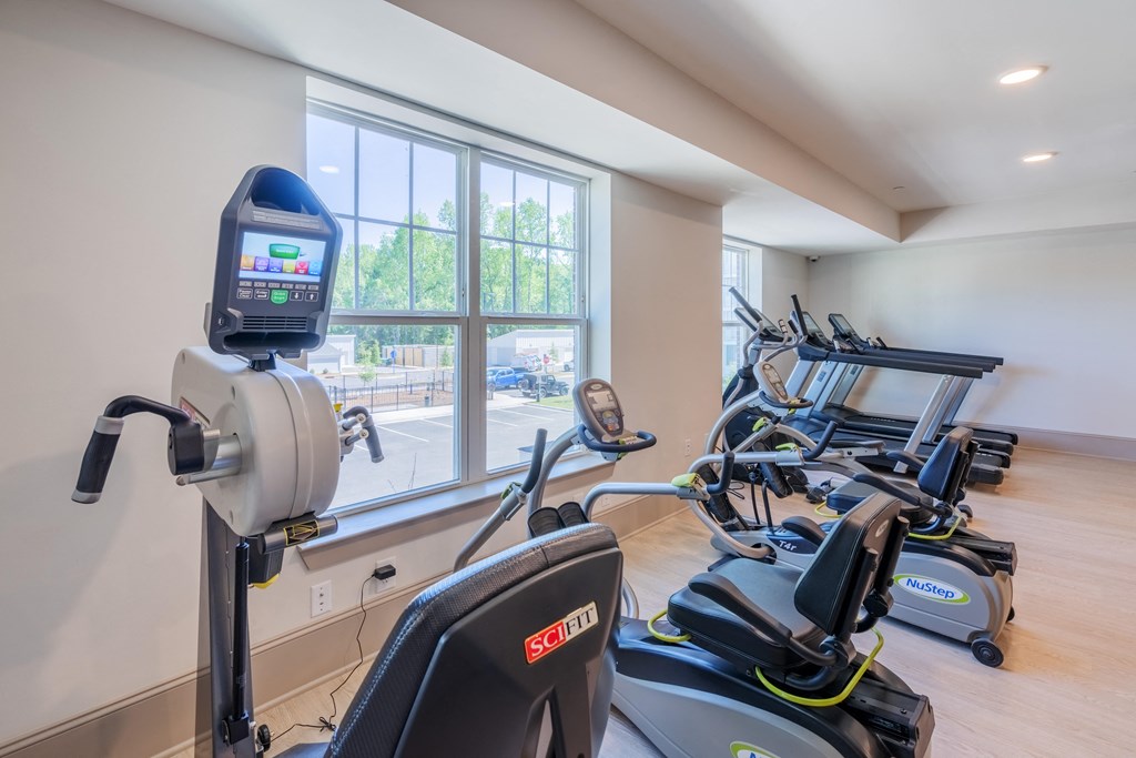 gym with exercise machines and windows at the district flats apartments in lenexa