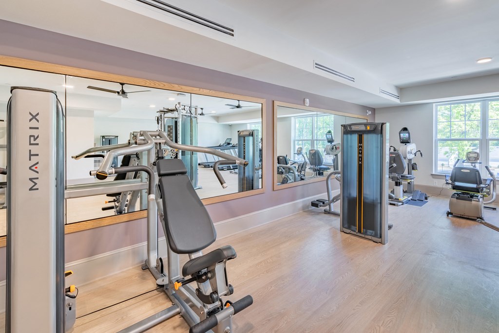 a gym with treadmills and other exercise equipment in a building with windows
