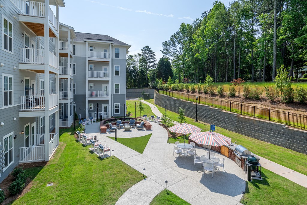 a courtyard with tables and umbrellas in front of an apartment building
