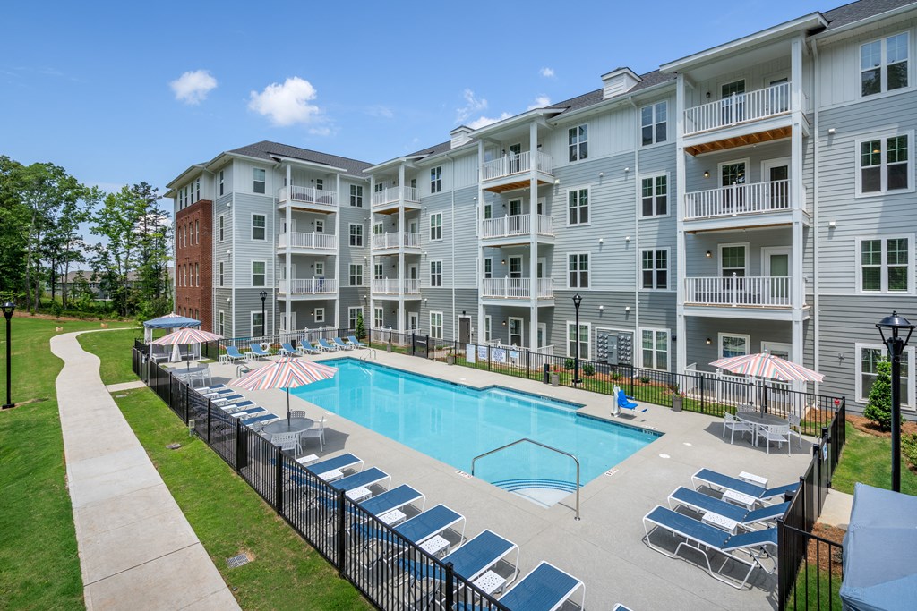 an apartment building with a swimming pool and lounge chairs