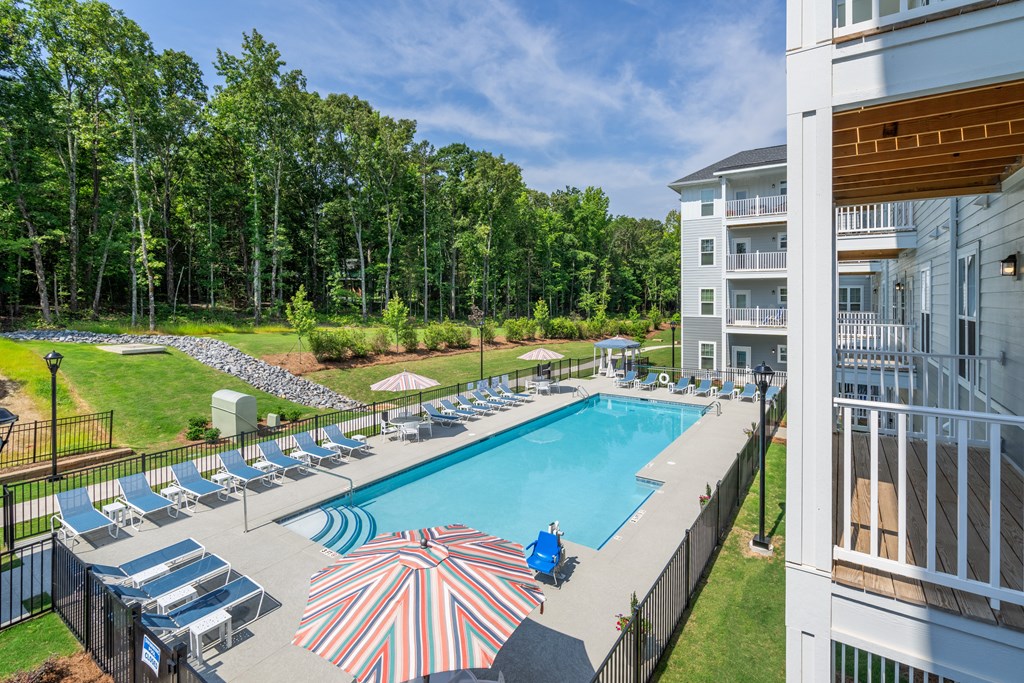 a swimming pool with chairs and umbrellas in front of a building