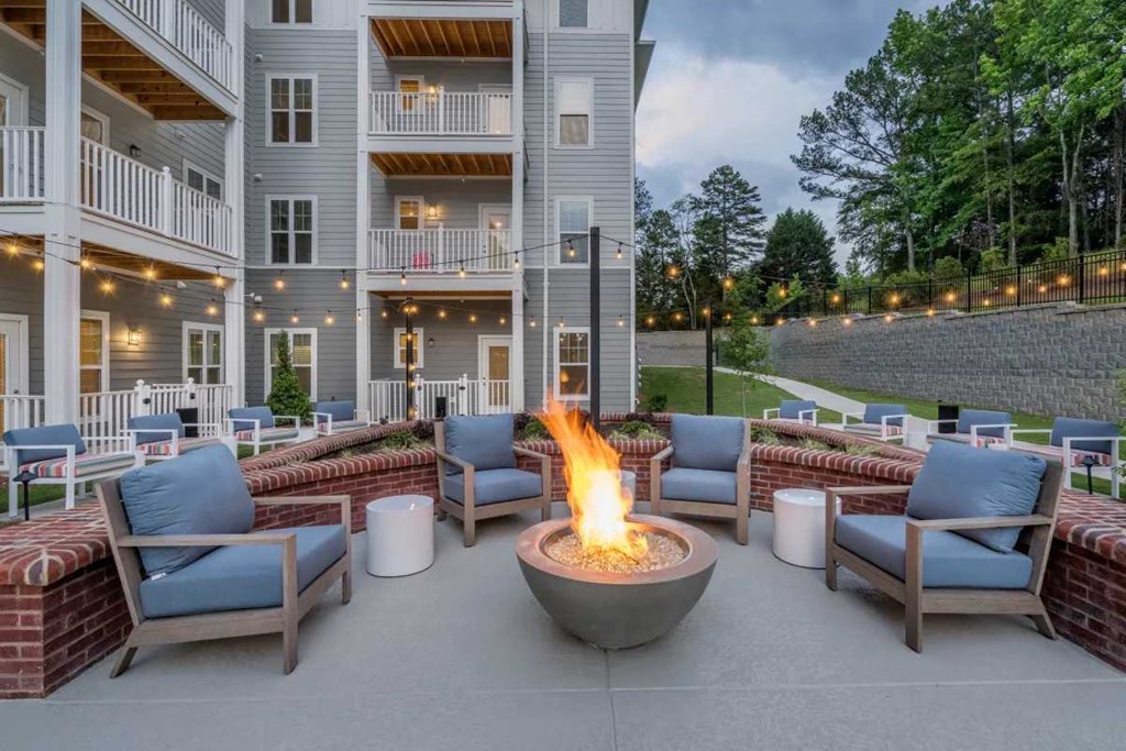 a fire pit in the middle of a patio with chairs and tables
