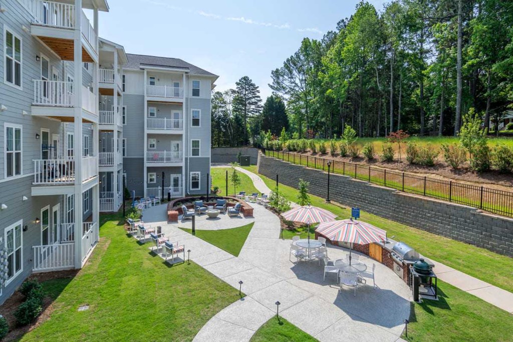 a courtyard with tables and umbrellas in front of an apartment building