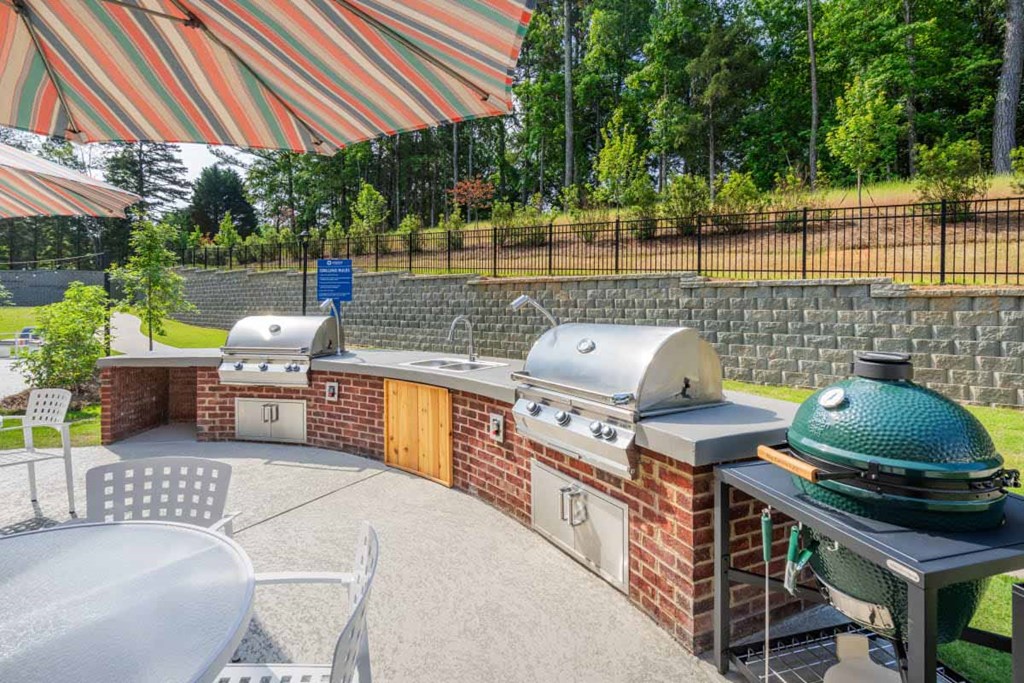 a patio with a barbecue grill and a table with chairs and an umbrella