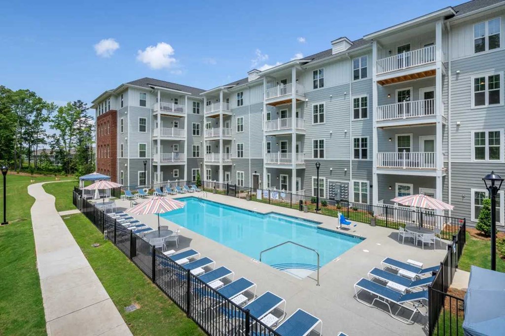 an apartment building with a swimming pool and lounge chairs