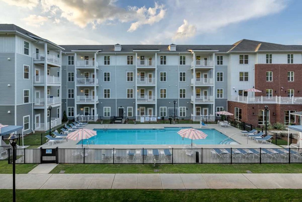 an apartment building with a swimming pool and umbrellas