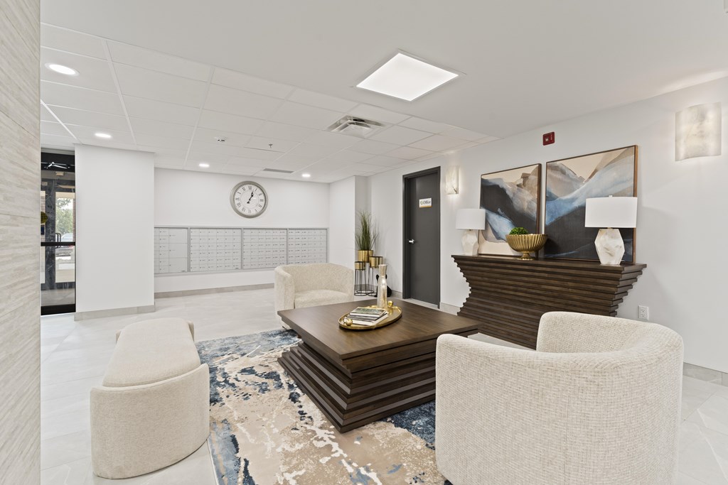 A modern office lobby with a white chair, a wooden coffee table, and a large rug.
