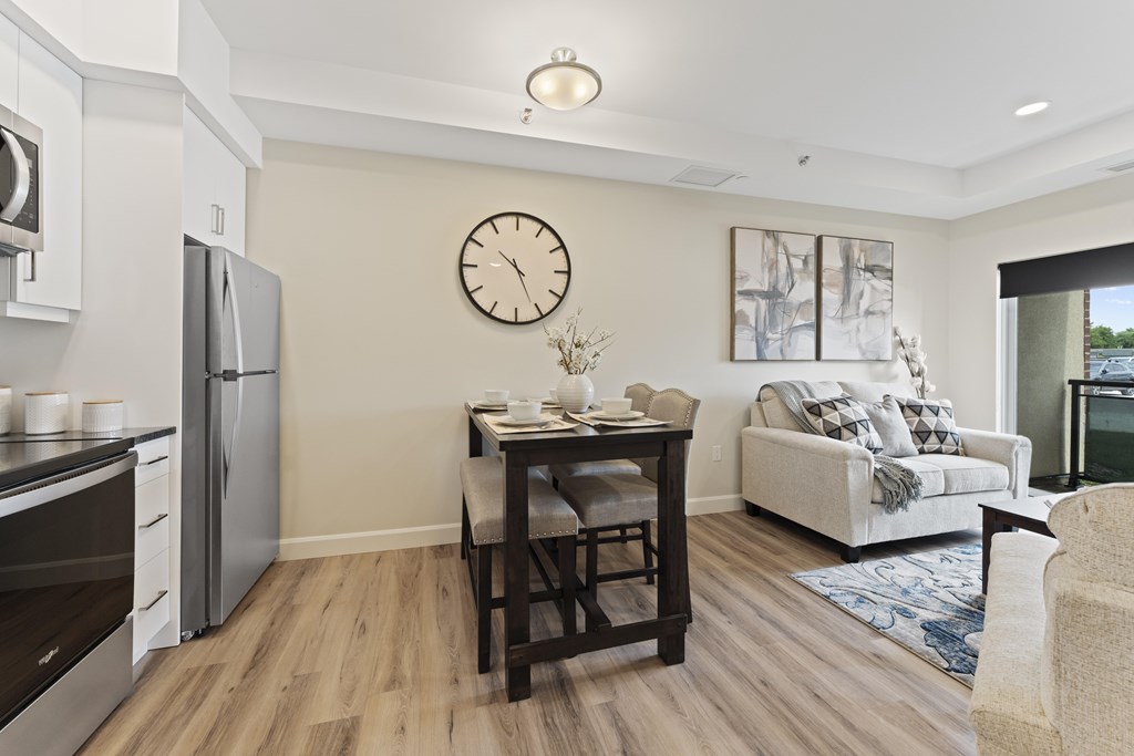 A kitchen with a refrigerator, oven, and a dining table with chairs.