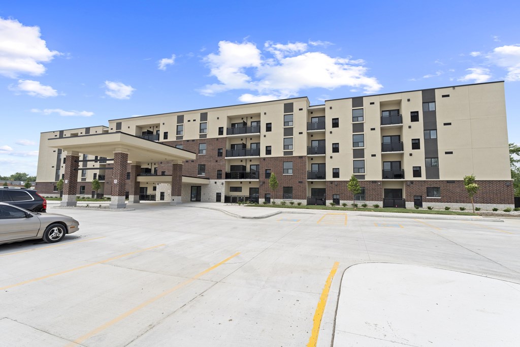 A parking lot in front of a large apartment building.