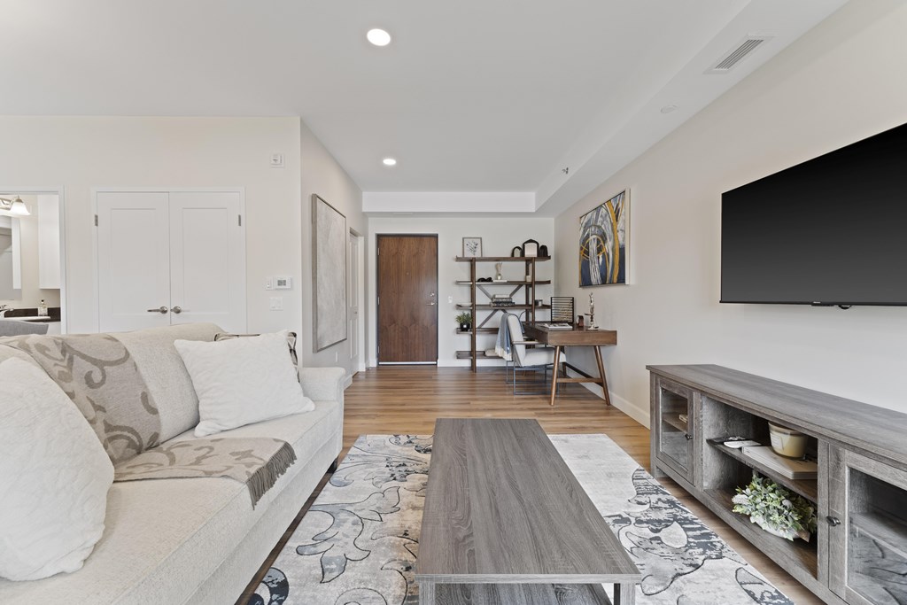 A modern living room with a white couch and a grey coffee table.