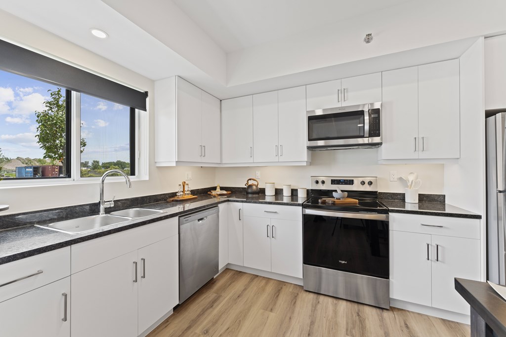 A modern kitchen with white cabinets and black countertops.