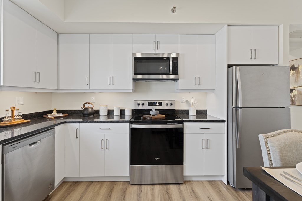 A modern kitchen with white cabinets and stainless steel appliances.