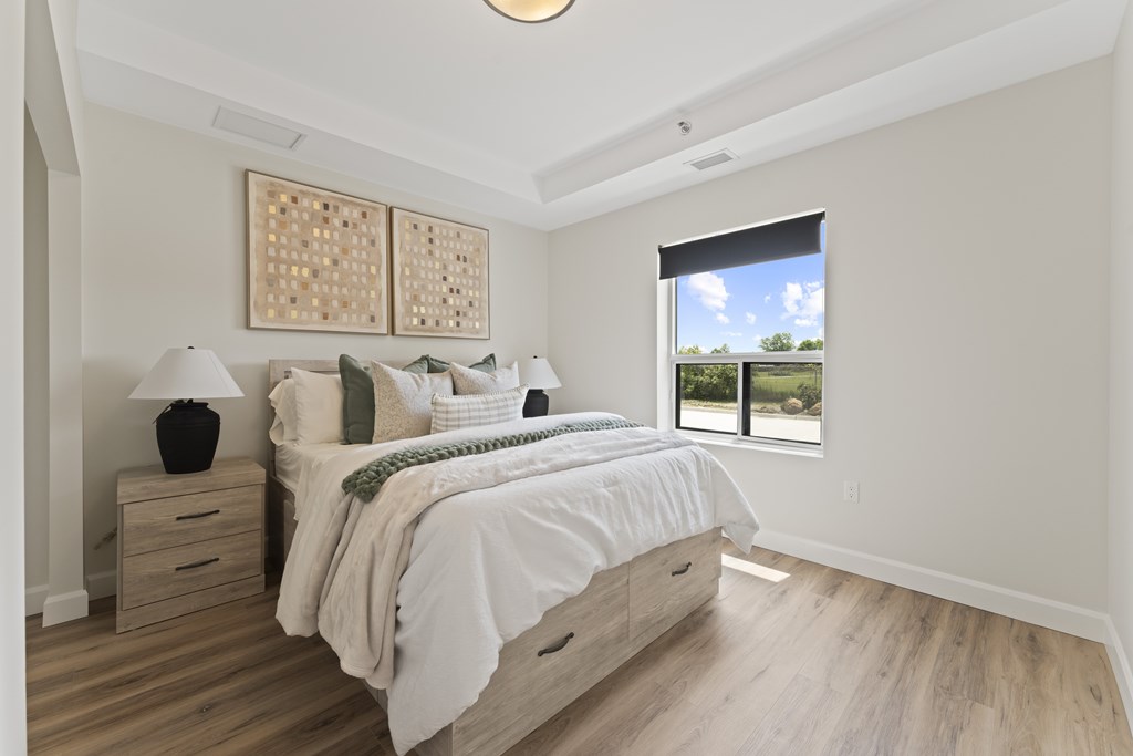 A bedroom with a large bed and a window overlooking a green landscape.
