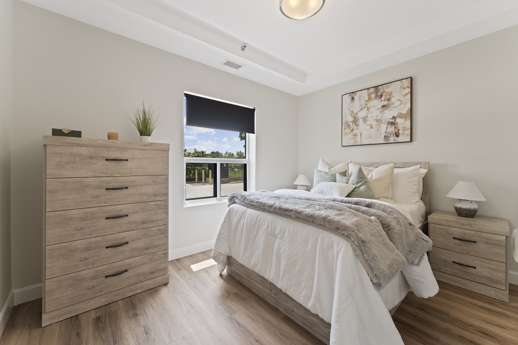 A bedroom with a large bed and a dresser with a plant on top.