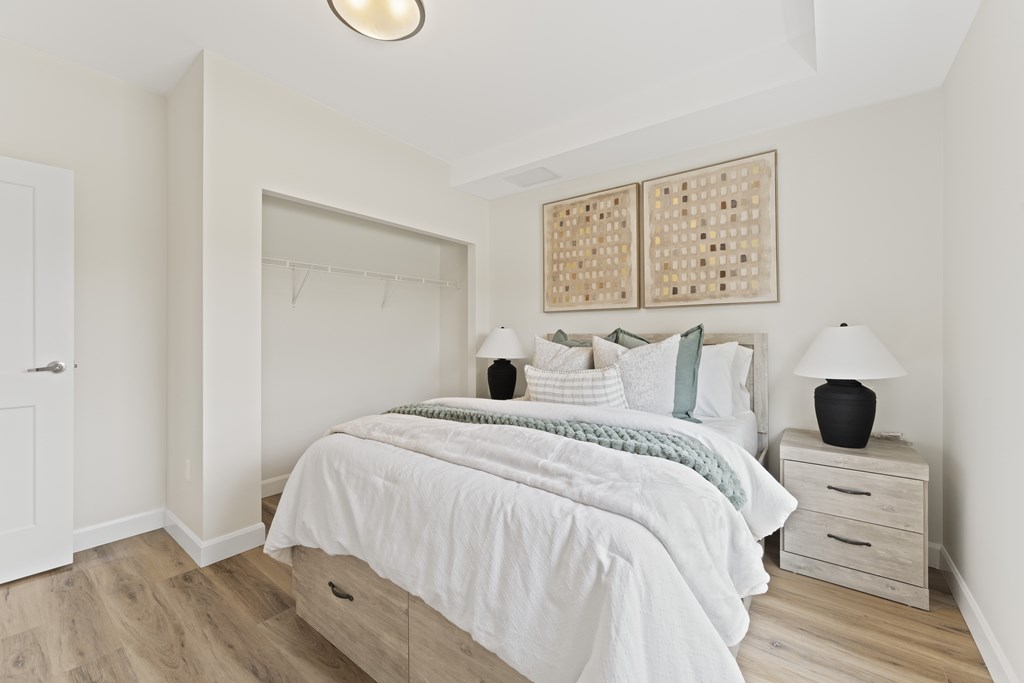 A bedroom with a large bed, a nightstand with a lamp, and a wall hanging.