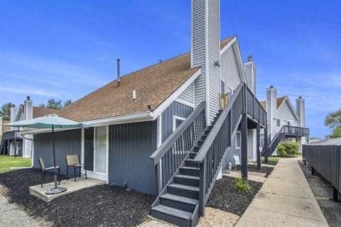 a gray house with stairs and a umbrella