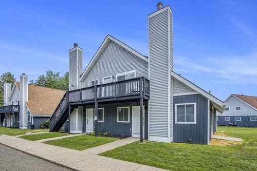 a gray house with a balcony on a sidewalk