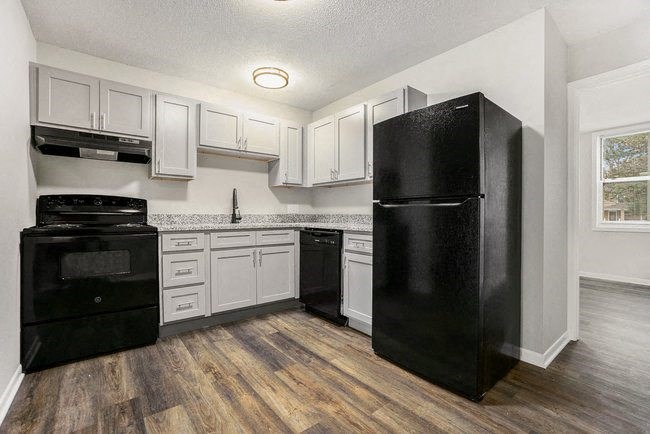 a kitchen with white cabinets and a black refrigerator