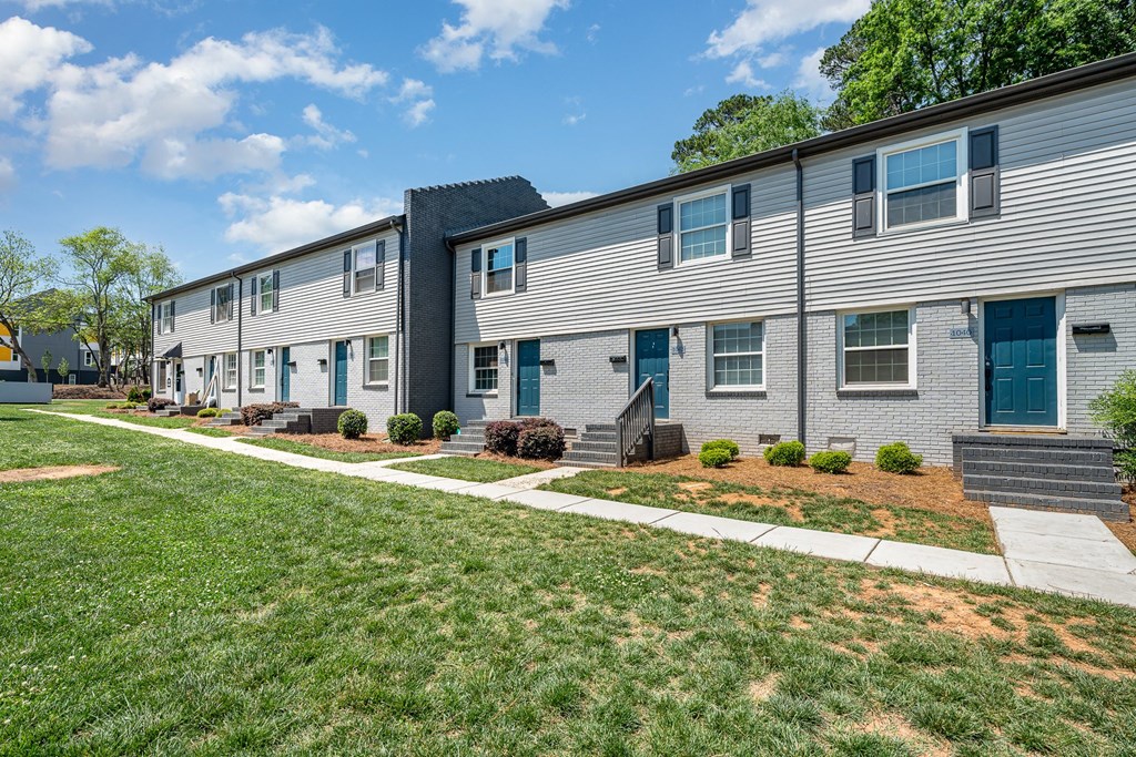 a white apartment building with blue doors and a lawn