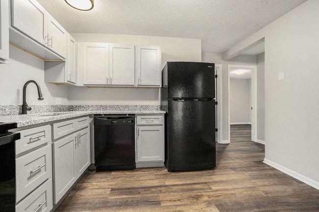 a kitchen with white cabinets and a black refrigerator