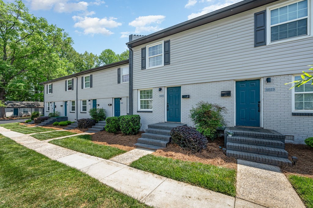 a white house with blue doors and a sidewalk
