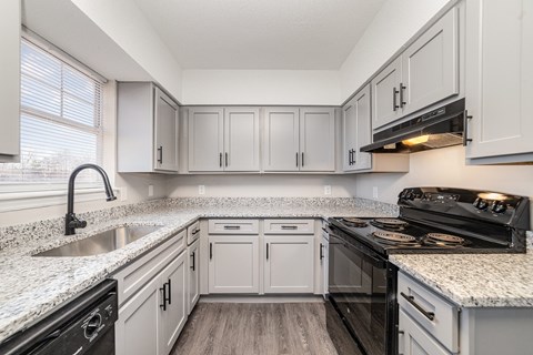 A kitchen with white cabinets and black appliances.